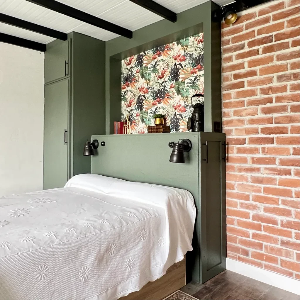Dormitorio con paredes verdes, papel pintado floral y pared de ladrillo