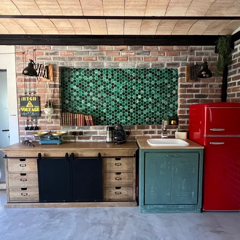 Cocina industrial con azulejos hexagonales verdes y nevera roja vintage