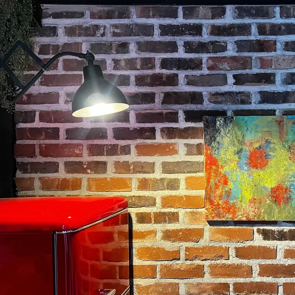 Pared de ladrillo visto con lámpara industrial y mueble rojo